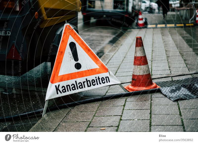 A warning sign warning triangle indicating sewer works on the road channel work Street Warning sign Warning triangle Signage Signs and labeling Characters Wet