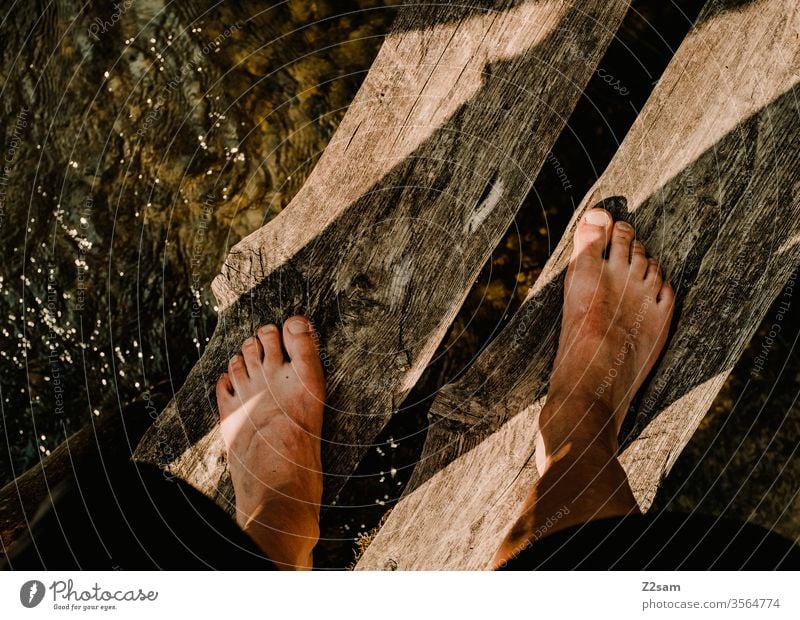 Man stands on wooden bridge over river foot Stand Water Nature River Barefoot Summer bathe Relaxation vacation Vacation & Travel Swimming & Bathing Colour photo