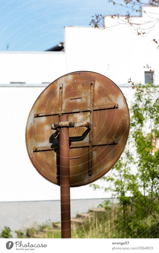 Rusty back of a traffic mirror in front of a white building facade Rear side Mirror traffic mirrors Old corroded Road equipment visibility Flip side