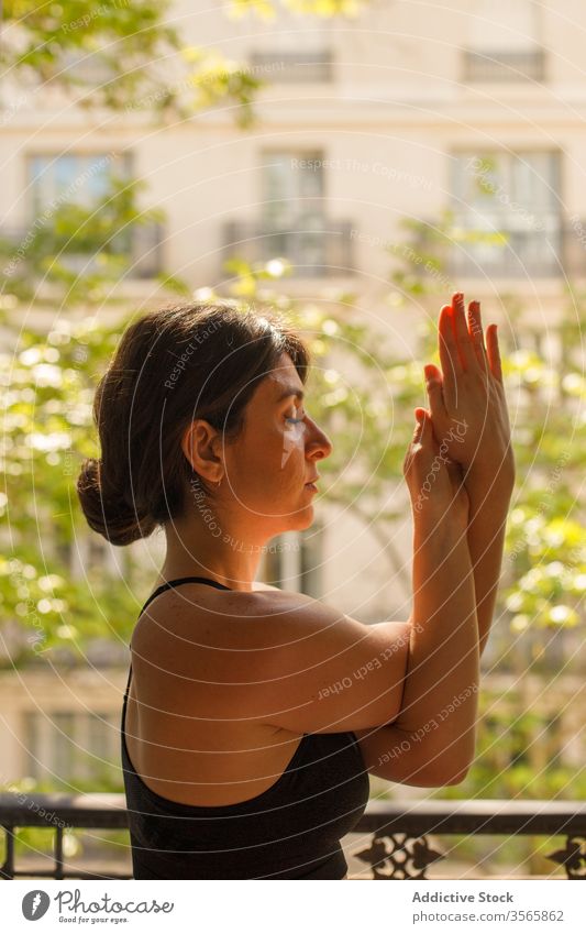 Calm female standing in eagle pose during yoga practice in summertime woman home meditate asana balcony calm peace mindfulness zen healthy lifestyle vitality