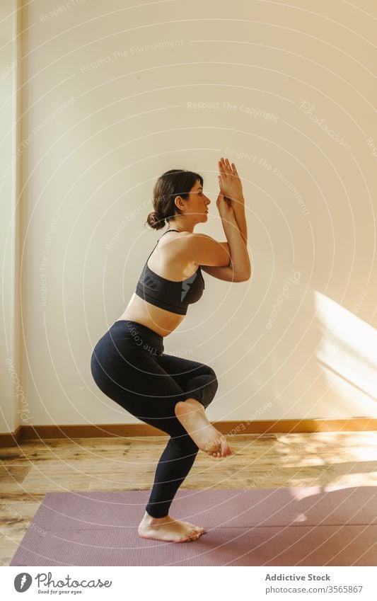 sportswoman standing in eagle pose on mat at home yoga balance meditate healthy lifestyle vitality practice wellness training flexible peaceful energy body