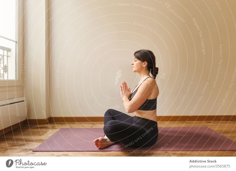 Tranquil woman meditating in Lotus pose lotus pose meditate yoga namaste padmasana mindfulness tranquil focus home female concentrate exercise mat training