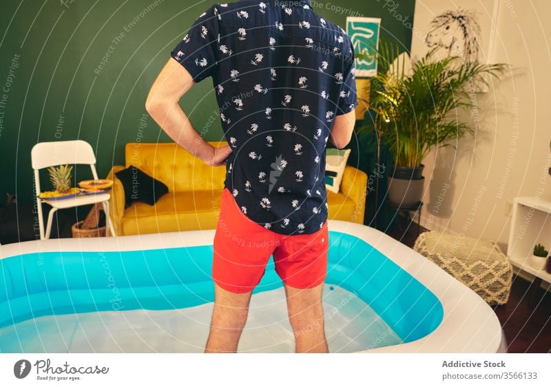 Man in inflatable pool during home party man stay at home summer apartment creative self isolation having fun water male shorts shirt social distancing outfit