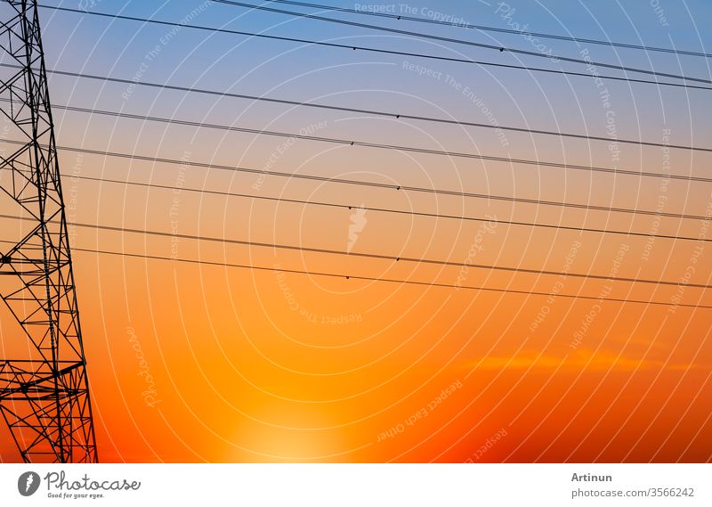 Silhouette high voltage electric pylon and electrical wire with an orange sky. Electricity poles at sunset. Power and energy concept. High voltage grid tower with wire cable at distribution station.