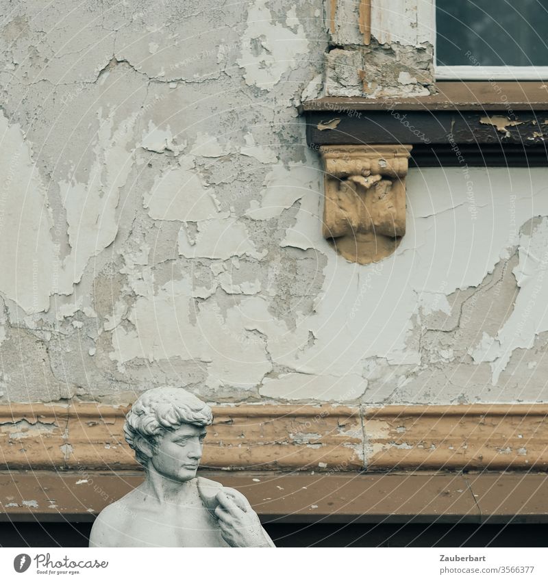 Head of a male statue in front of a facade with flaking paint and stucco detail of a window Facade Statue Roman Rome Flake off Brown Gray Old Window slice