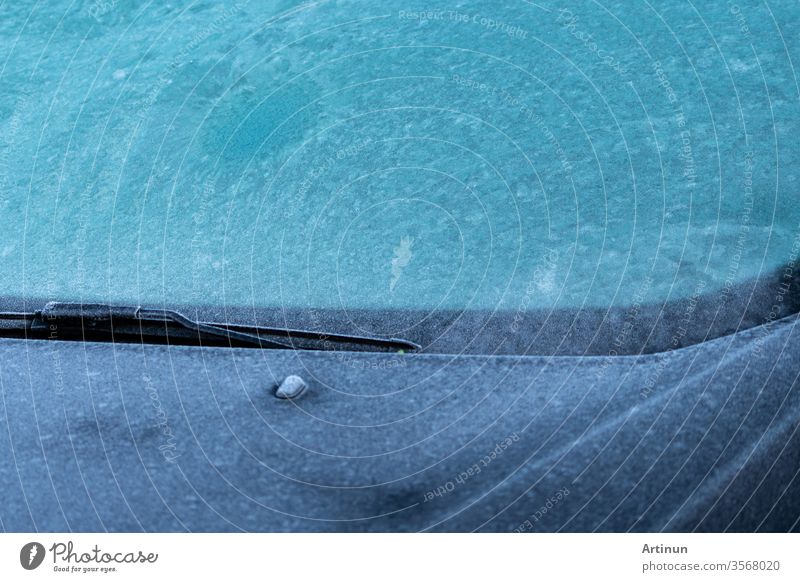 Closeup front view of car parked at outdoor car parking lot that windshield and bonnet covered by freezing rain and small ice pellet. Climate change concept. Environment warning. Texture of ice pellet