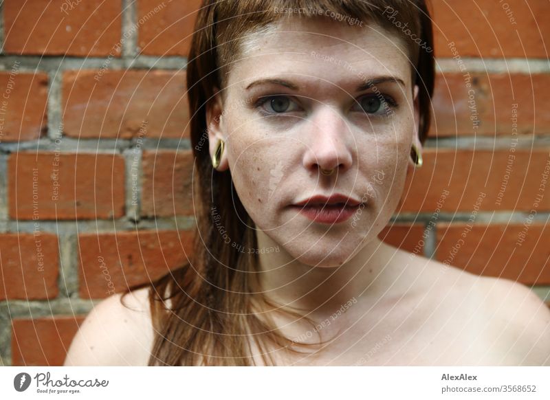 Portrait of a young woman in front of a brick wall Woman Youth (Young adults) already Strong Alternative great Piercing Skin Intensive Looking look watch Stand