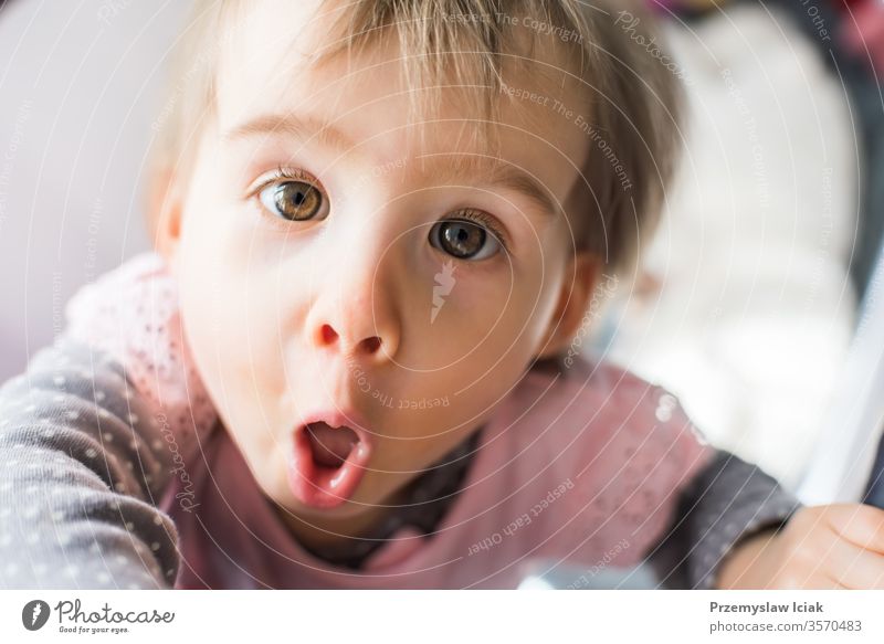 Funny baby in the crib in bright room. face expression bed development curosity funny sweet adorable girl child one year old age growth head hair learning