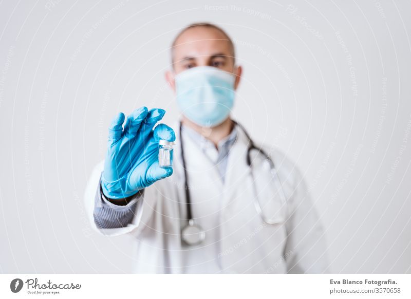 doctor man holding a vial. using protective mask and gloves during corona virus covid 2019 pandemic. Health care and medical concept syringe cod-2019 tube