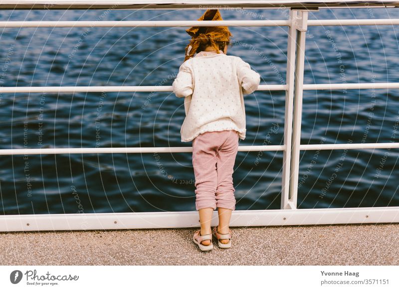 Child looks through the parapet into the sea Sand Beach Ocean Water Waves Surf Coast Sky Blue Clouds Horizon Nature Far-off places Landscape White