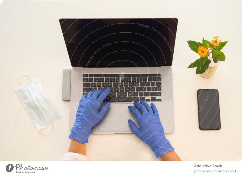 Woman with protective mask and gloves using laptop coronavirus home work remote workplace hand gadget device safety covid covid 19 covid19 pandemic epidemic