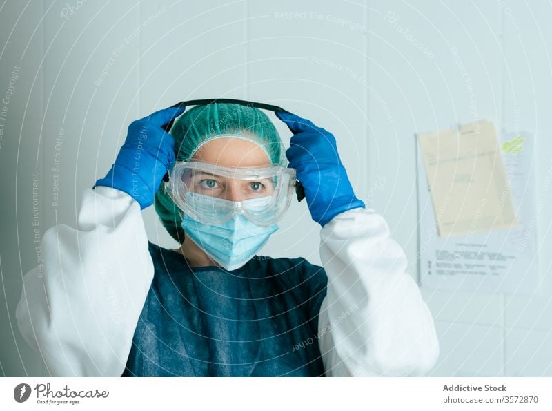 Female doctor in protective mask and goggles medical coronavirus covid woman nurse safety wear put on uniform disease covid19 covid 19 pandemic epidemic