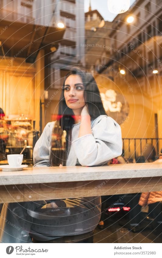 Cheerful young woman sitting in cafe cheerful trendy style enjoy coffee window female counter drink cozy cafeteria relax happy lifestyle city rest smile break