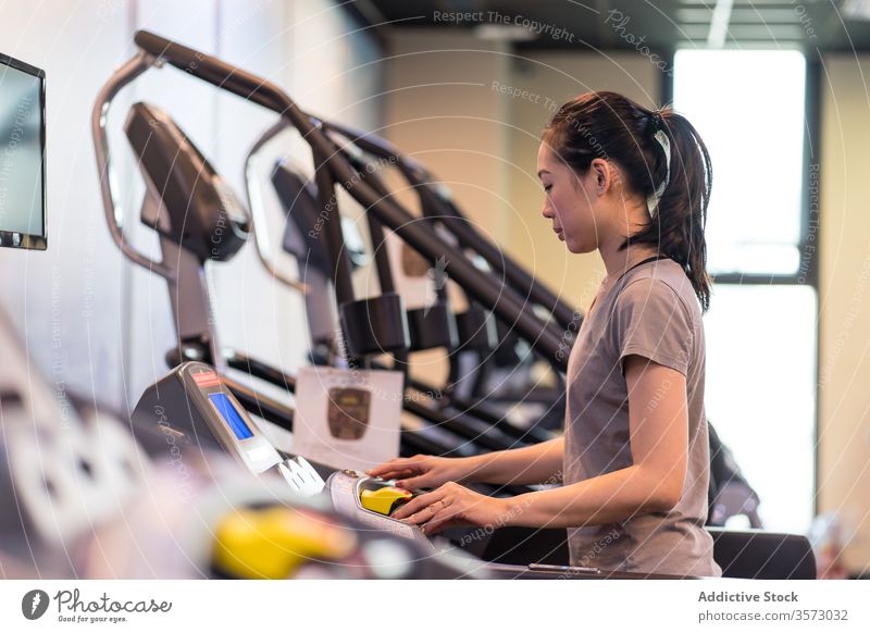 Young ethnic sportswoman running on treadmill while training in modern gym cardio exercise athlete healthy workout fitness slim young active wear wellness