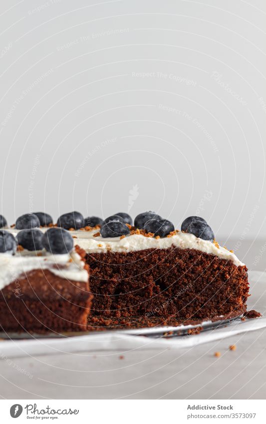 Piece of fresh chocolate cake decorated with blueberries and cream on table in kitchen piece whipped slice sponge biscuit white blueberry food dessert sweet