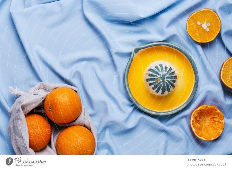 Flatlay of cut oranges and ceramic hand squeeze juicer on blue drapery citrus delicious food fresh fruit healthy ingredient kitchen organic sweet tasty teal