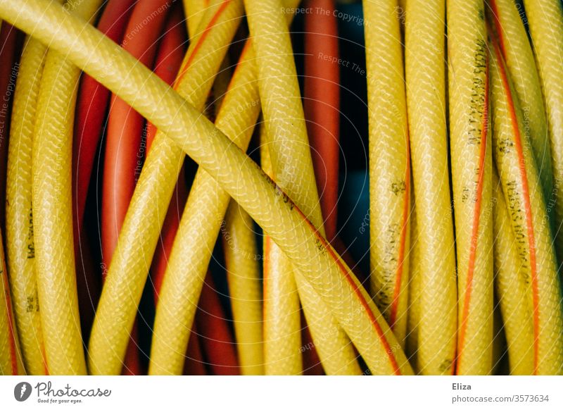 Close-up of a yellow garden hose Garden hose Water hose Yellow Cast Gardening detail coiled Hose Near Orange