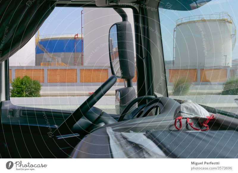 Truck interior, dashboard with a mask and fuel storage tanks in the background truck fuels rearview deposits steering wheel transport vehicle cabin cockpit