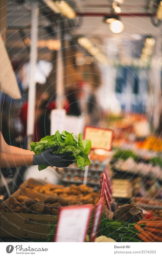 Weekly market - saleswoman holds fresh salad in her hands Marketplace Farmer's market Lettuce carrots tute Customers by hand Vegetable Market stall