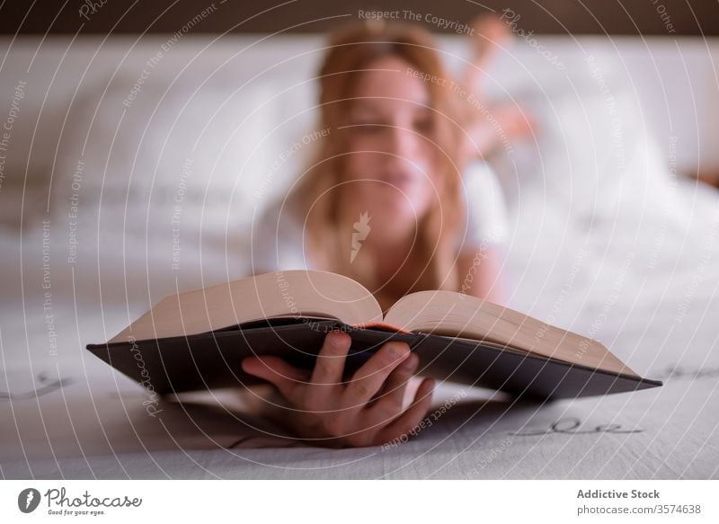 Lazy young ginger woman with book on bed in weekend peaceful lazy dream relax read be my love female lying stomach redhead red hair white t shirt romantic decor