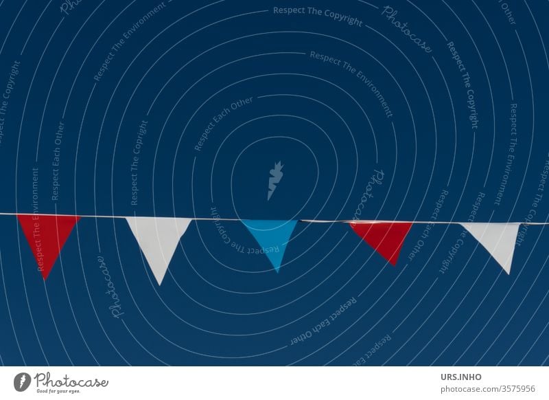 Pennants in the colours red, white, blue on a rope in front of a neutral blue background flag Red White Blue Flag colours pennant pennant chain