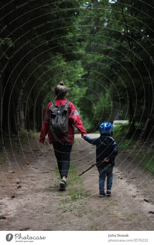 Woman walking with child in the forest Forest forest path Earth Fir cone huts Spruce forest Bike helmet Hiking stroll Walking Chignon fleece jacket Rain jacket