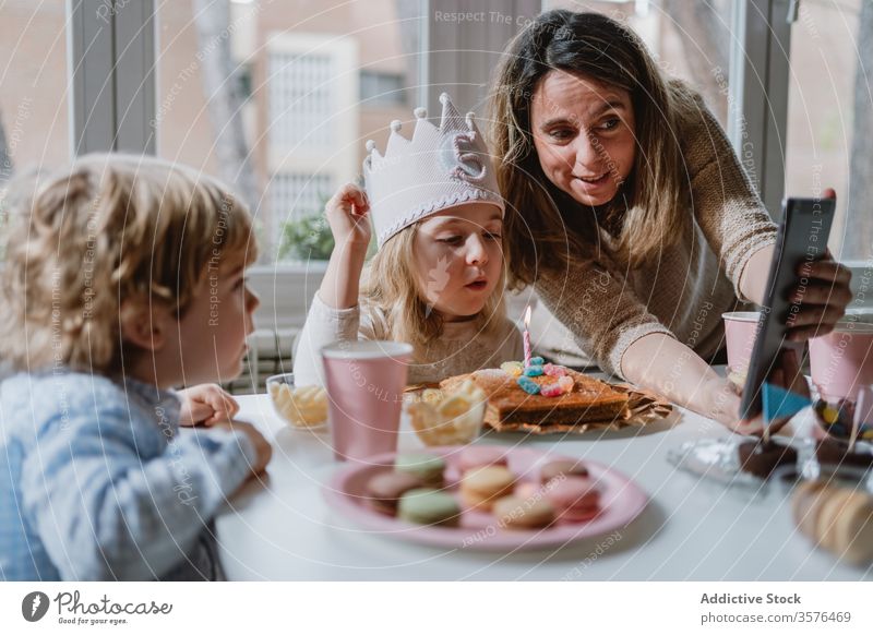 Cheerful little girl making video call on tablet during birthday celebration mother daughter celebrate fun happy remote home distance positive kid mobile phone