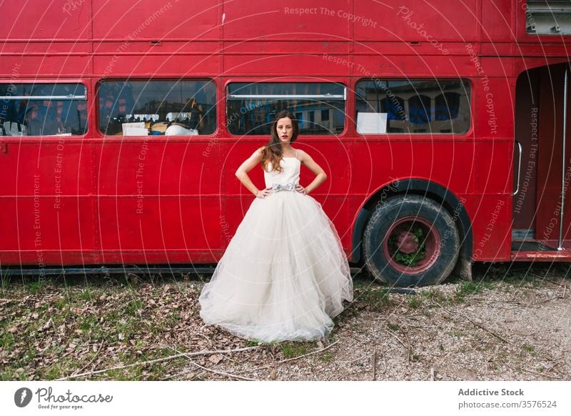 Serious bride standing near red double decker bus newlywed red bus wedding wood wedding dress retro serious unemotional female elegant forest wedding day