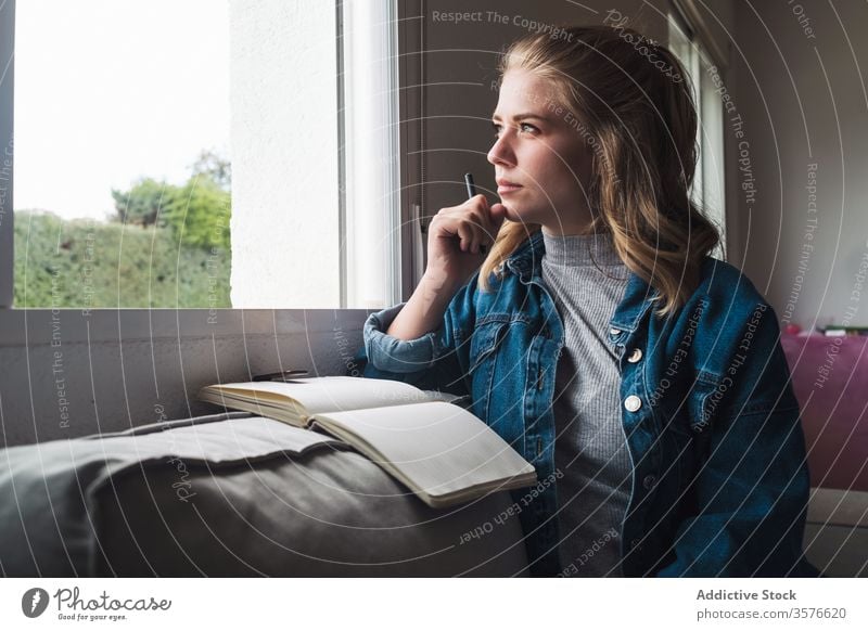 Pensive woman with notebook sitting near window diary home pensive young student notepad thoughtful read casual female think calm tranquil concentrate ponder