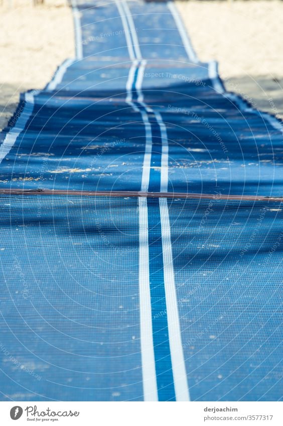 Rolled out. Long blue runner with white stripes, with pleats, located on the edge of the sea access only for disabled people. Carpet Runner Floor covering Blue