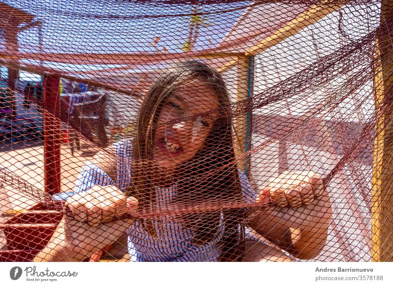 Pretty little girl dressed in a white and blue striped dress locked in a net covered cage. Isolation concept book wooden decoration planked globe child