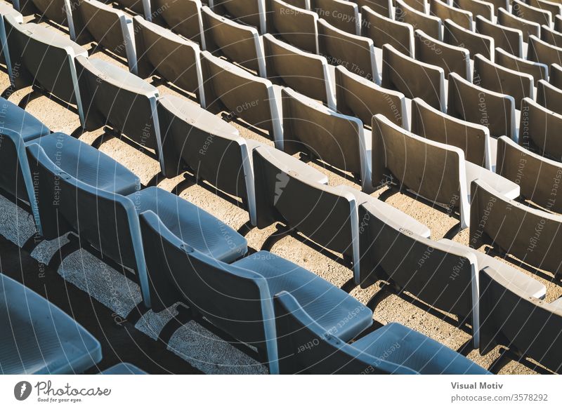 Rows of empty seats of a large outdoor stadium on a sunny day before sports event bleacher row public plastic facility chair aisle contemporary structure