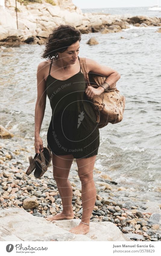 A beautiful female Latina carrying a bag and a slippers in the shore woman girl beauty young white pretty people attractive adult smiling happy portrait