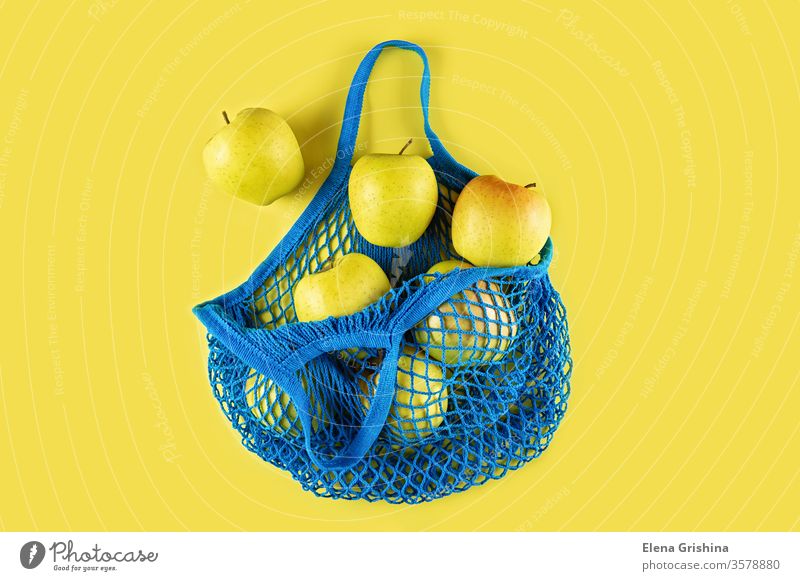 Ripe apples in a blue string bag on a yellow background. zero waste eco bag mesh bag cotton ecology concept ecological natural reusable recycle lifestyle