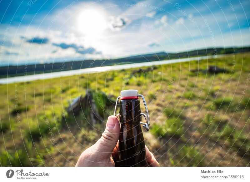 Enjoy life. Cheers! bottle Neck of a bottle Bottle of beer Beer swing stopper office Sun Back-light Lake Drinking Beverage Glassbottle by hand open Beer garden