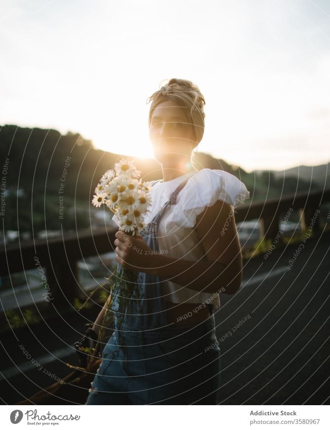 Positive young female with bouquet of fresh chamomile resting with dog on road woman flower fun happy present give charming summer friend companion positive