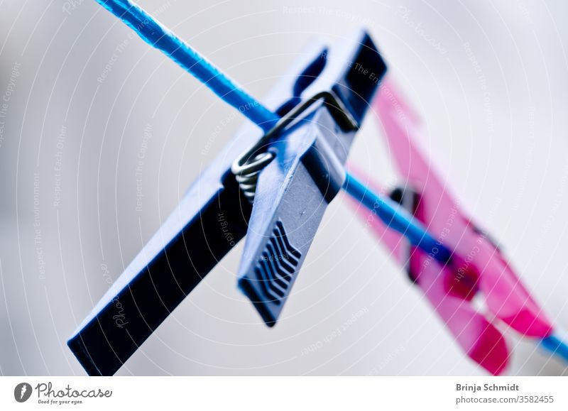 A blue and a pink clothespin hanging from a blue clothesline, close-up Many Weather macro Abstract colourful Colour Plastic Line Rope Clamp Old bokeh Wash Cable