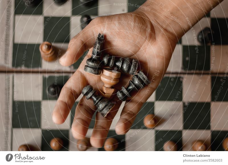 a hand holding five chess pieces Black White Hand Chessboard Chess piece Brown Move (board game) Grasp Square Wood grain Classic Brainteaser Rustic Wooden board