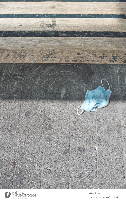 discarded used mouthguard lies under a wooden bench corona pandemic Street Town urban Wooden bench S-Bahn station Stop (public transport) Park bench