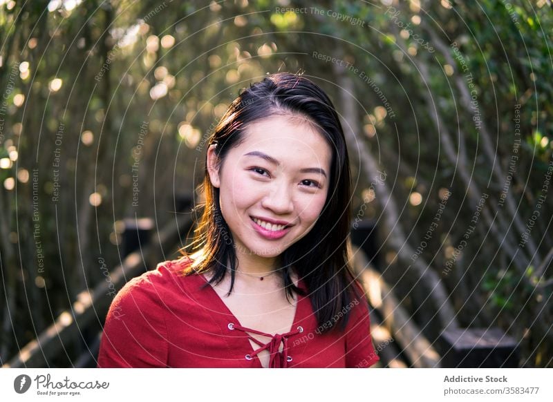 Dreamy young Asian woman standing in park contemplate calm dreamy feminine mouth opened human face necklace quiet think serene summer youth peaceful tree