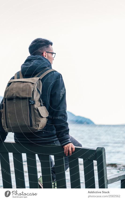 Male traveler sitting at rocky seaside man backpack rest enjoy freedom nature scotland highland glen coe male hiker coast adventure journey tourism trip shore