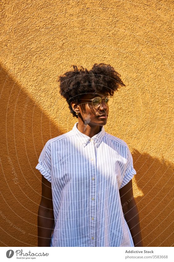 Stylish pensive black woman on street in sunny day personality trendy colorful afro tranquil thoughtful glasses calm brunette female slim slender fashion