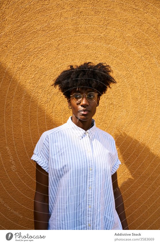 Stylish pensive black woman on street in sunny day personality trendy colorful afro tranquil thoughtful glasses calm brunette female slim slender fashion