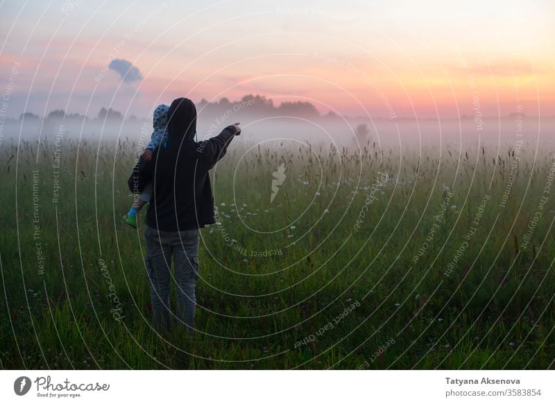 Father holding little son and showing him something far in fog father dad child family together wellbeing safety parent baby boy field foggy evening night