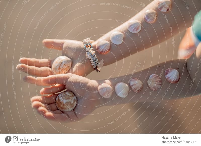 Little girls' hands with the seashells on them on the ocean sandy beach background. child kid love seashore summer sun outdoor nature lifestyle toddler travel