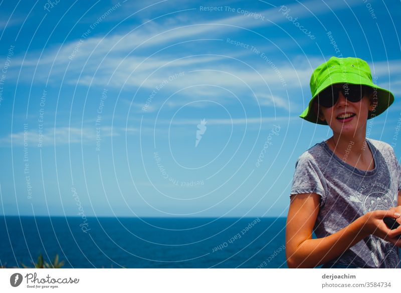 The " New " hat looks good on me. A girl with new hat in green, stands on the sea beach. In the background the Pacific. Girls hat Close-up girls pretty Summer