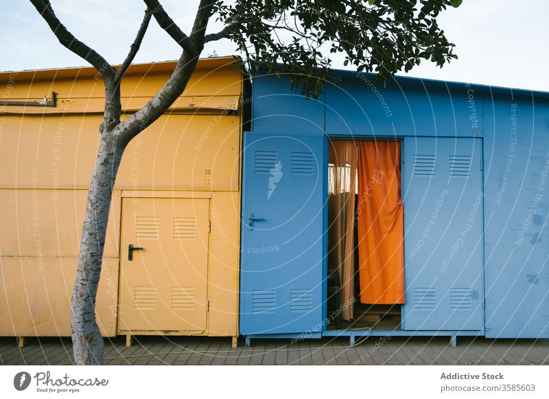 Colorful utility buildings on pavement ground yellow blue metallic weathered urban area tree colorful composition sunny summer day clear sky blue sky exterior