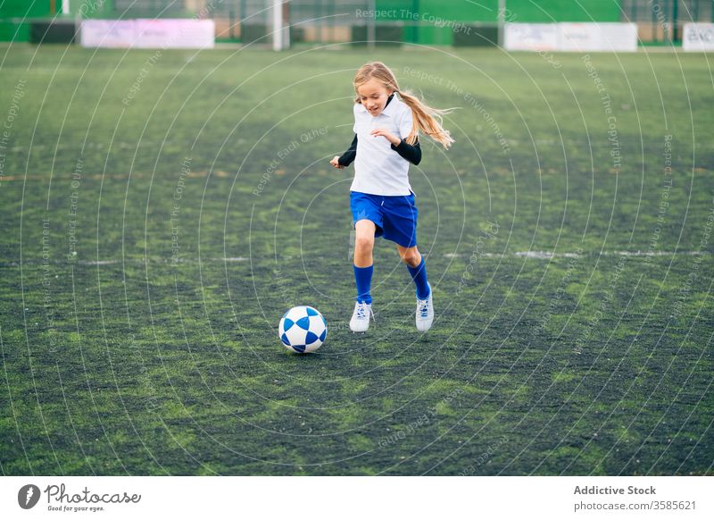 young female player playing football at sports stadium girl soccer field kid run uniform club training child game activity athlete equipment kick focus