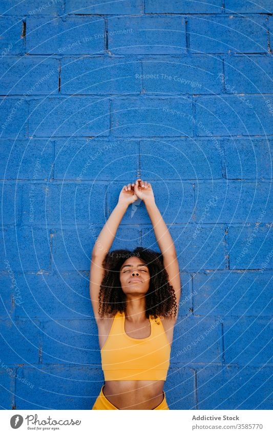 Dreamy African American woman leaning on wall in street dreamy daydream afro color vivid vibrant tranquil stone wall female ethnic black african american yellow