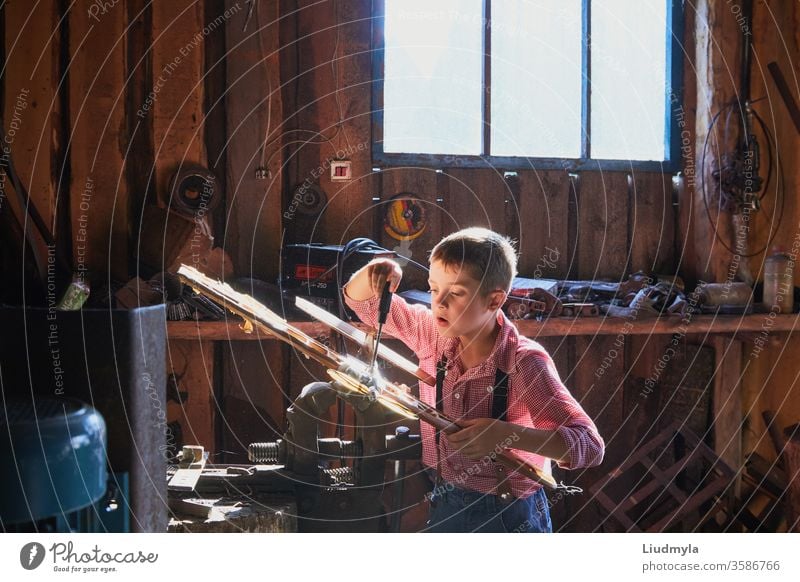 A curious boy is trying to fix an old wooden handmade plane in a carpentry workshop. toy aeroplane making preschool model creating learning air happy handyman